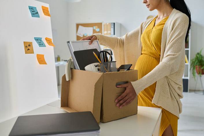 Pregnant woman packing up office supplies - Pregnancy Discrimination